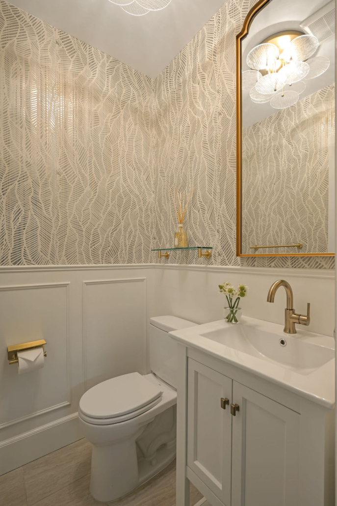 Refined powder room with textured wall covering, brass fixtures, and white vanity styled by Orlie Katsiris Staging & Interiors.