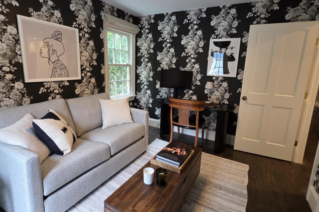Cozy den staged by Orlie Katsiris Staging & Interiors featuring a neutral sofa, layered textiles, wood coffee table, and statement wallpaper.