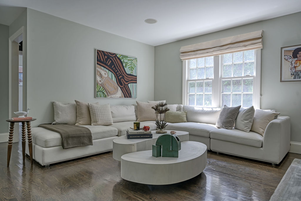 Bright living room staged by Orlie Katsiris Staging & Interiors featuring neutral sofas, a round coffee table, layered textiles, and natural light in a Sag Harbor residence.