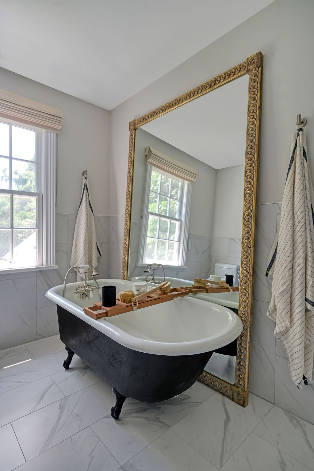 Elegant primary bath styled by Orlie Katsiris Staging & Interiors featuring a freestanding tub, oversized mirror, and calm neutral palette.