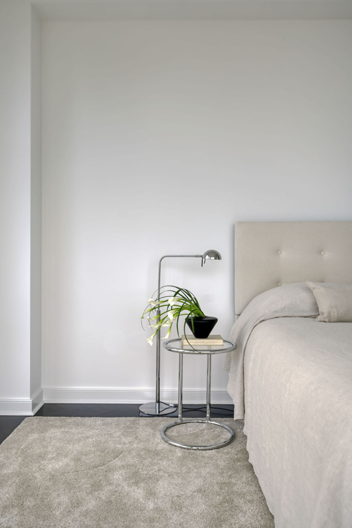 Minimalist bedroom design by Orlie Katsiris Staging & Interiors with a light upholstered bed, sculptural bedside table, neutral textiles, and calm modern styling.